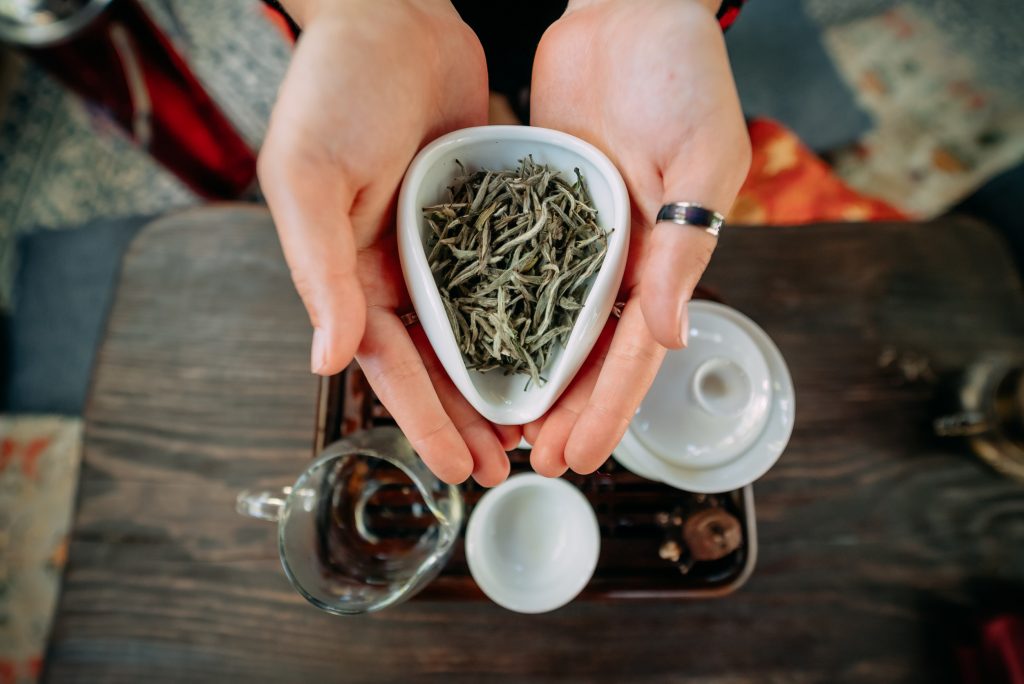 Young woman holding a small bowl of green herbal tea, close view