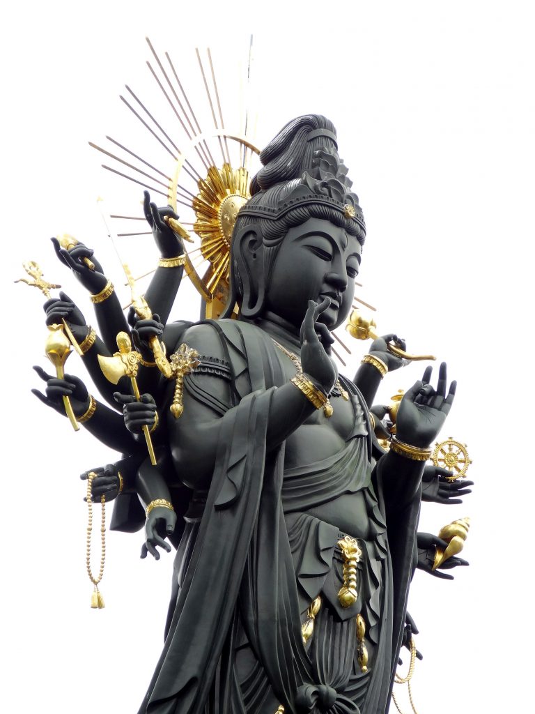 black and gold sculpture of kuan yin goddess of mercy with many arms