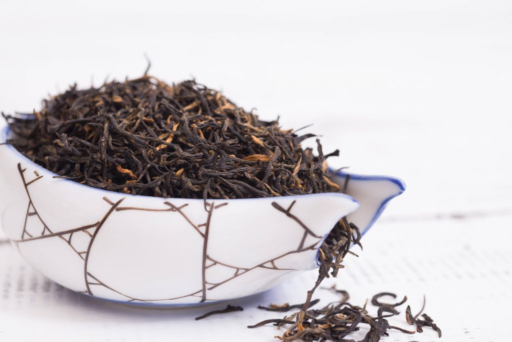 the dry leaves of golden monkey tea in a white holder