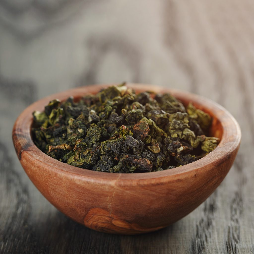 oolong green tea in olive bowl, on oak table